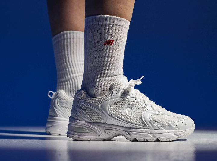 Helhvite sneakers (new balance 530) på fot med hvite tennissokker fra New Balance.