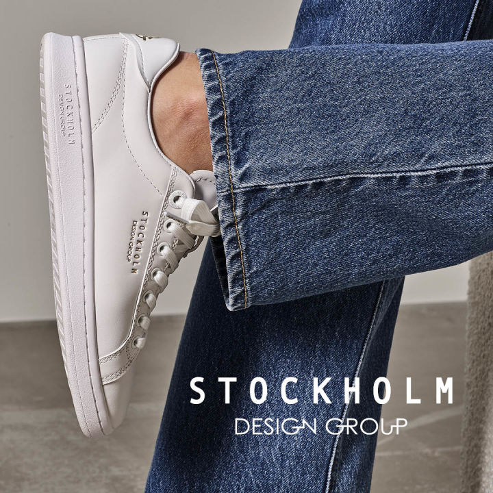 Hvit sko på fot med mørke jeans. SDG-logo ved siden av.